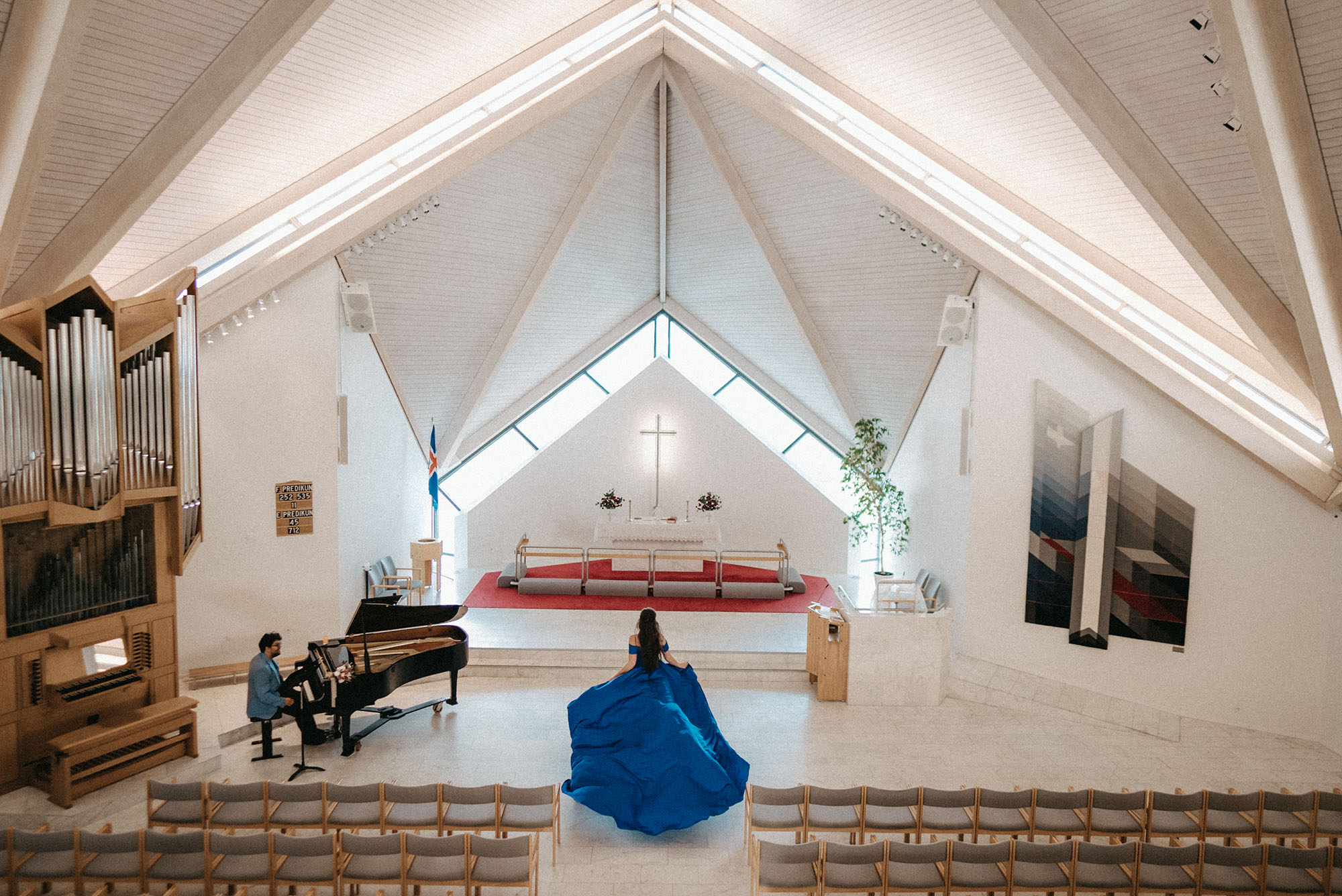 Bride in a blue wedding dress running toward the altar while groom plays piano.