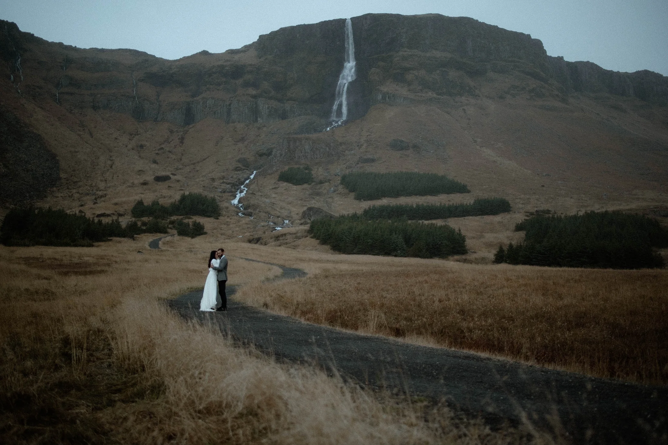 Couple beneath a distant waterfall in Iceland