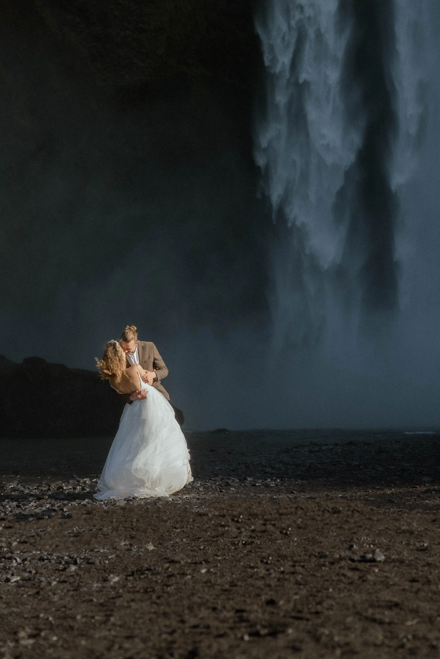Couple standing beside a powerful Iceland waterfall